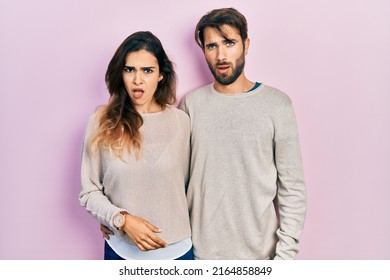 Young Hispanic Couple Wearing Casual Clothes In Shock Face, Looking Skeptical And Sarcastic, Surprised With Open Mouth 