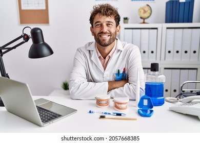 Young hispanic dentist man working at medical clinic happy face smiling with crossed arms looking at the camera. positive person.  - Powered by Shutterstock