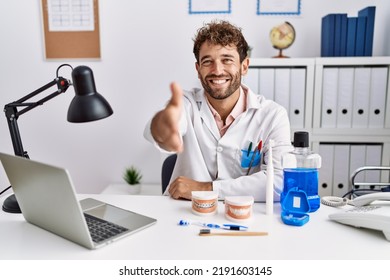 Young Hispanic Dentist Man Working At Medical Clinic Smiling Friendly Offering Handshake As Greeting And Welcoming. Successful Business. 