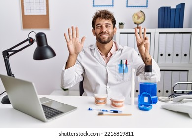 Young Hispanic Dentist Man Working At Medical Clinic Showing And Pointing Up With Fingers Number Eight While Smiling Confident And Happy. 