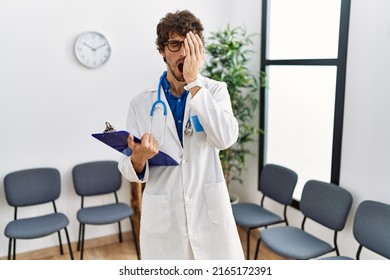 Young Hispanic Doctor Man At Waiting Room Yawning Tired Covering Half Face, Eye And Mouth With Hand. Face Hurts In Pain. 