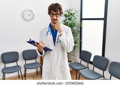 Young Hispanic Doctor Man At Waiting Room Pointing To The Eye Watching You Gesture, Suspicious Expression 