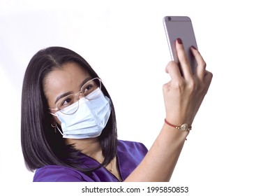 A Young Hispanic Doctor Nurse Wearing Glasses And A Sanitary Mask Taking A Selfie