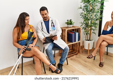 Young Hispanic Doctor And Patinent Woman Looking Diagnosis Sitting At Medical Clinic Waiting Room