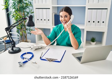 Young Hispanic Doctor Woman Speaking On The Phone At The Clinic Celebrating Achievement With Happy Smile And Winner Expression With Raised Hand 