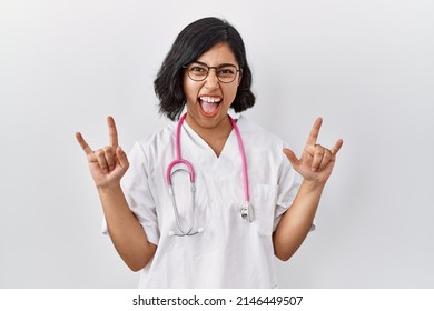 Young Hispanic Doctor Woman Wearing Stethoscope Over Isolated Background Shouting With Crazy Expression Doing Rock Symbol With Hands Up. Music Star. Heavy Concept. 