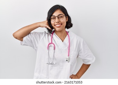 Young Hispanic Doctor Woman Wearing Stethoscope Over Isolated Background Smiling Doing Phone Gesture With Hand And Fingers Like Talking On The Telephone. Communicating Concepts. 