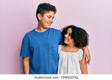 Young Hispanic Family Of Brother And Sister Wearing Casual Clothes Together Smiling Looking To The Side And Staring Away Thinking. 