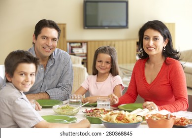 Young Hispanic Family Enjoying Meal At Home