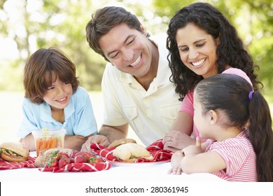 Young Hispanic Family Enjoying Picnic In Park