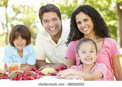 Young Hispanic Family Enjoying Picnic In Park