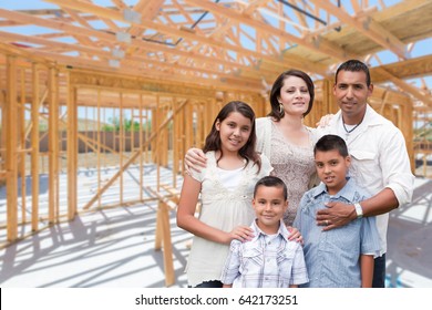 Young Hispanic Family On Site Inside New Home Construction Framing.