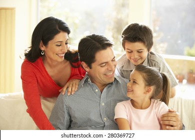 Young Hispanic Family Relaxing On Sofa At Home