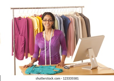 Young Hispanic Fashion Designer Standing At Work Table With Computer