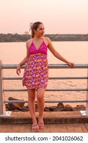 A Young Hispanic Female Standing On A Pier During The Sunset