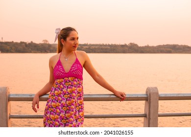 A Young Hispanic Female Standing On A Pier During The Sunset