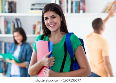 Young hispanic female student with group of young adults at classroom of university