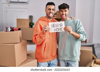 Young Hispanic Gay Couple Moving To A New Home Sticking Tongue Out Happy With Funny Expression. 