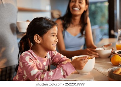 Young hispanic girl enjoying her breakfast with a smile. Mixed race daughter in pajamas eating corn flakes immersed in a cup of milk in kitchen. Close up of joyful indian cute little girl eating. - Powered by Shutterstock