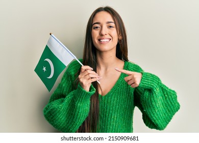 Young Hispanic Girl Holding Pakistan Flag Smiling Happy Pointing With Hand And Finger 