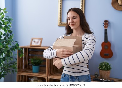 Young Hispanic Girl Opening Cardboard Box Winking Looking At The Camera With Sexy Expression, Cheerful And Happy Face. 