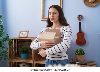 Young Hispanic Girl Opening Cardboard Box Depressed And Worry For Distress, Crying Angry And Afraid. Sad Expression. 