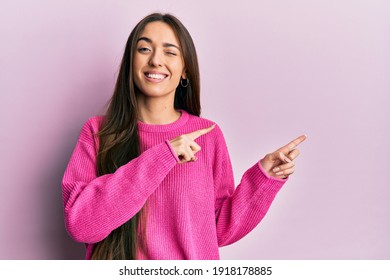 Young hispanic girl pointing with fingers to the side winking looking at the camera with sexy expression, cheerful and happy face. 