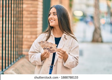 Young hispanic girl smiling happy holding mexican 500 pesos banknotes at the city.
