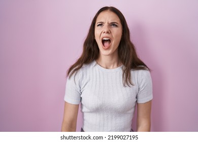 Young hispanic girl standing over pink background angry and mad screaming frustrated and furious, shouting with anger. rage and aggressive concept.  - Shutterstock ID 2199027195