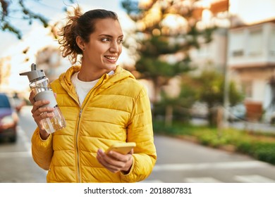 Young Hispanic Girl Using Smartphone And Drinking Water At The City.