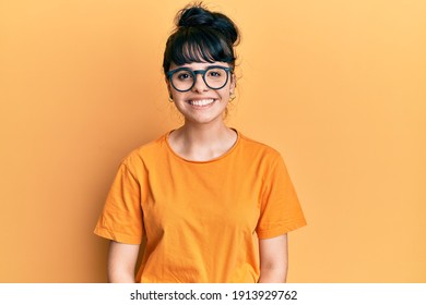 Young hispanic girl wearing casual clothes and glasses looking positive and happy standing and smiling with a confident smile showing teeth 