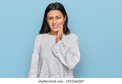 Young hispanic girl wearing casual clothes touching mouth with hand with painful expression because of toothache or dental illness on teeth. dentist 