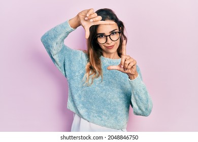 Young hispanic girl wearing casual clothes and glasses smiling making frame with hands and fingers with happy face. creativity and photography concept. 