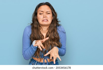 Young hispanic girl wearing casual clothes disgusted expression, displeased and fearful doing disgust face because aversion reaction. 