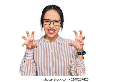 Young hispanic girl wearing casual clothes and glasses smiling funny doing claw gesture as cat, aggressive and sexy expression 