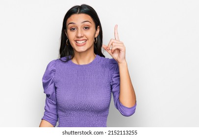 Young hispanic girl wearing casual clothes pointing finger up with successful idea. exited and happy. number one. 