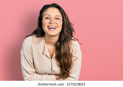 Young hispanic girl wearing casual clothes and glasses smiling and laughing hard out loud because funny crazy joke. 