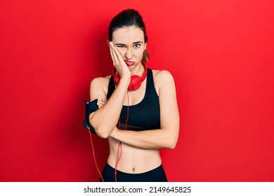 Young Hispanic Girl Wearing Gym Clothes And Using Headphones Thinking Looking Tired And Bored With Depression Problems With Crossed Arms. 