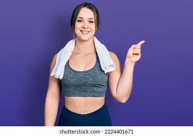 Young Hispanic Girl Wearing Sportswear And Towel With A Big Smile On Face, Pointing With Hand Finger To The Side Looking At The Camera. 