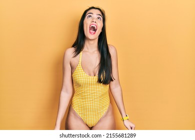 Young hispanic girl wearing swimsuit angry and mad screaming frustrated and furious, shouting with anger. rage and aggressive concept. 