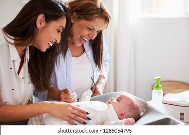 Young Hispanic Grandmother And Adult Daughter Playing With Her Baby Son On Changing Table, Close Up