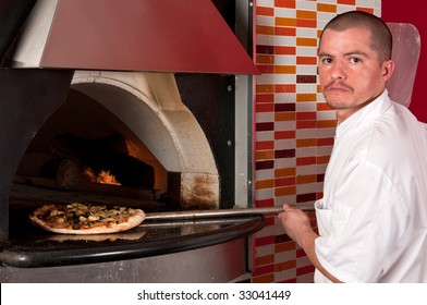 Young Hispanic Immigrant Cooking Pizza In A Restaurant.