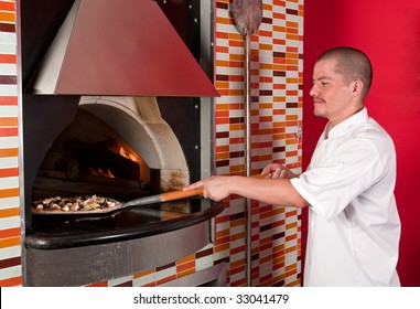 Young Hispanic Immigrant Cooking Pizza In A Restaurant.