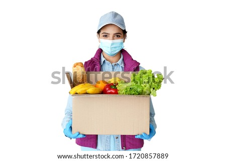 Young hispanic indian woman courier worker wears medical face mask, gloves looking at camera holding grocery food delivery box in hands concept stand isolated on white studio background. Portrait