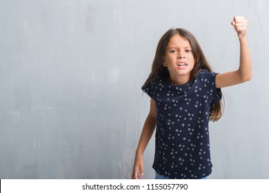 Young Hispanic Kid Over Grunge Grey Wall Angry And Mad Raising Fist Frustrated And Furious While Shouting With Anger. Rage And Aggressive Concept.