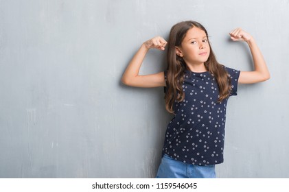 Young Hispanic Kid Over Grunge Grey Wall Showing Arms Muscles Smiling Proud. Fitness Concept.