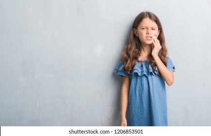 Young Hispanic Kid Over Grunge Grey Wall Touching Mouth With Hand With Painful Expression Because Of Toothache Or Dental Illness On Teeth. Dentist Concept.