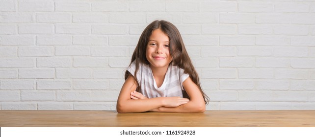 Young Hispanic Kid Sitting On The Table At Home With A Happy And Cool Smile On Face. Lucky Person.