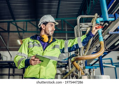 Young Hispanic Latin Engineer Working In A Heavy Industrial Factory. Worker Control Oil Gas Water Pipe In Plant.