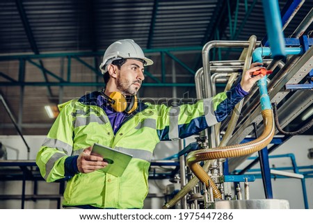 Young hispanic latin engineer working in a heavy industrial factory. worker control oil gas water pipe in plant.